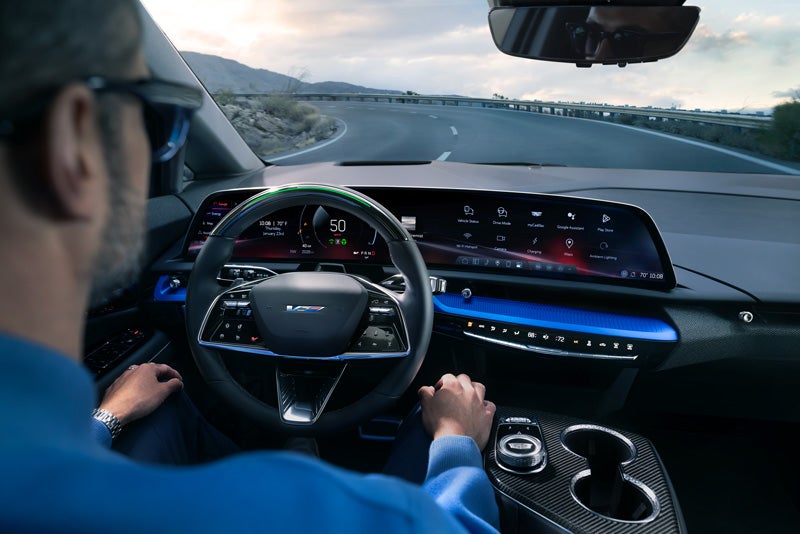 Front View of the 2026 OPTIQ-V Driving Through the Dusk Utilizing its Headlights | Colonial Cadillac in Woburn MA